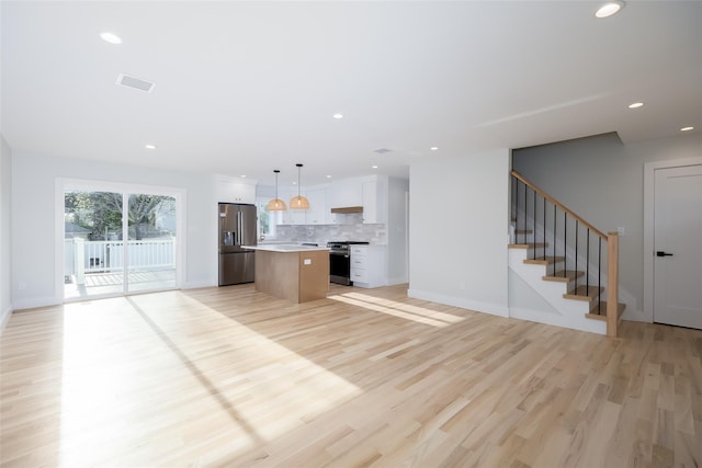 unfurnished living room featuring visible vents, recessed lighting, light wood finished floors, and stairs
