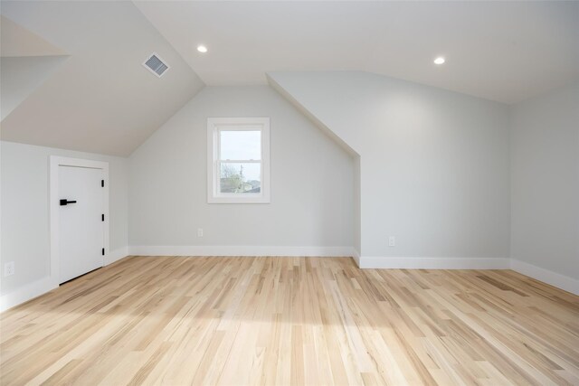 additional living space featuring visible vents, baseboards, lofted ceiling, and light wood-type flooring