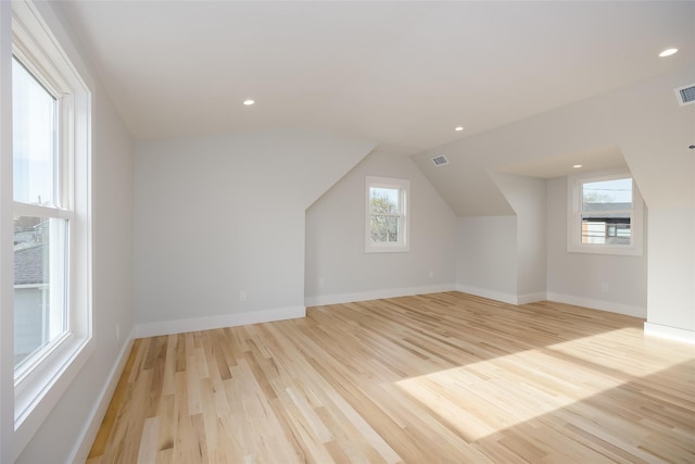 additional living space featuring baseboards, visible vents, light wood-style floors, and lofted ceiling