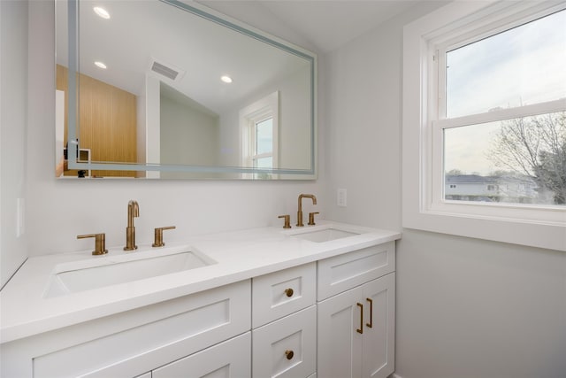 bathroom featuring visible vents, recessed lighting, double vanity, and a sink