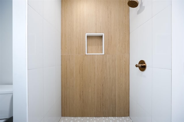 full bathroom featuring a tile shower and toilet
