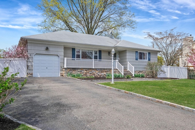 single story home featuring a porch, fence, a garage, driveway, and a front yard