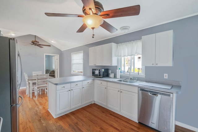 kitchen featuring appliances with stainless steel finishes, white cabinets, a sink, a ceiling fan, and a peninsula