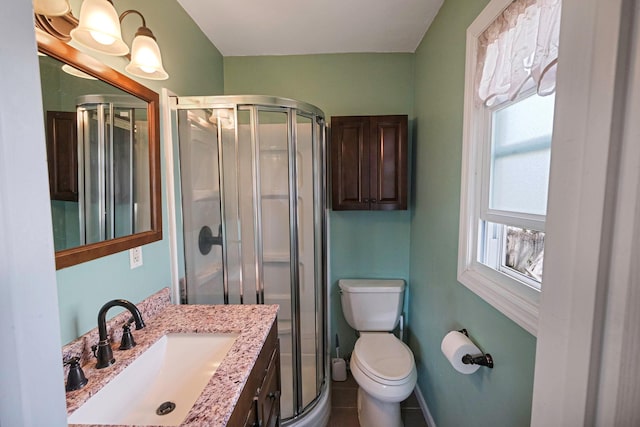 bathroom featuring vanity, toilet, a stall shower, baseboards, and tile patterned flooring
