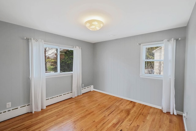 unfurnished room with a healthy amount of sunlight, baseboards, and light wood-type flooring