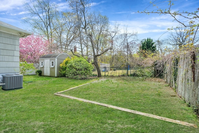 view of yard with a shed, a fenced backyard, central AC unit, and an outdoor structure