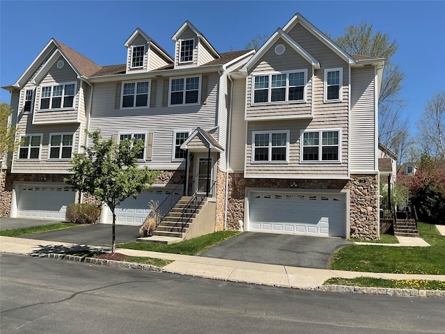 multi unit property with a garage, driveway, and stone siding