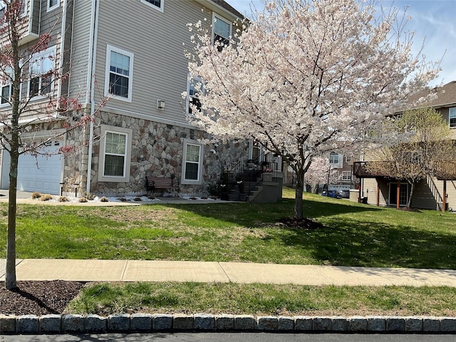 view of side of property with stairs, a yard, and stone siding
