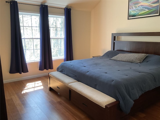 bedroom with baseboards, multiple windows, and wood finished floors