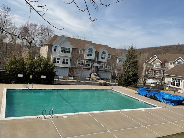 community pool featuring fence and a residential view