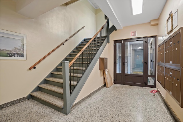 stairway featuring baseboards, speckled floor, and mail area