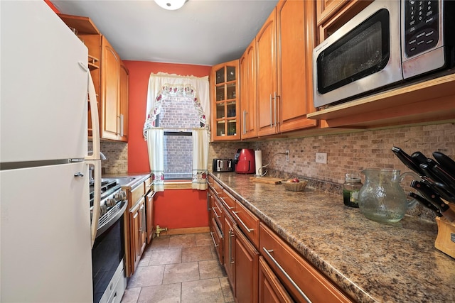 52-15 65th Pl Unit 2A, Maspeth, NY 11378 - kitchen with appliances with stainless steel finishes, backsplash, glass insert cabinets, brown cabinetry, and light stone finish floors