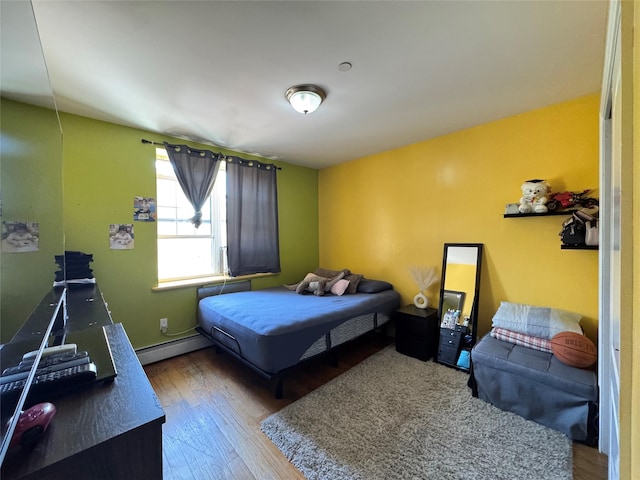 bedroom featuring baseboard heating and wood finished floors