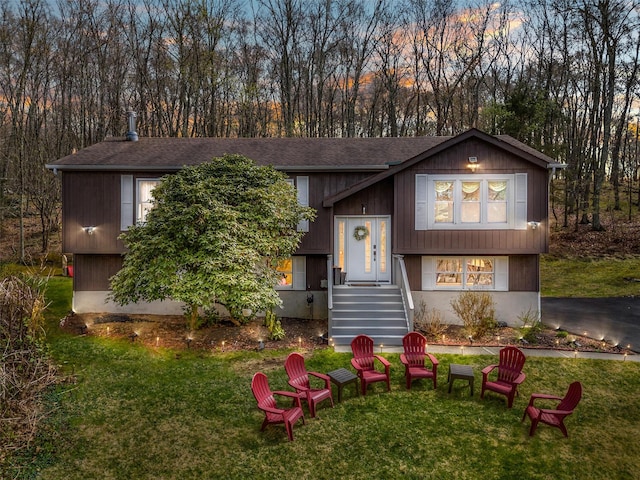 raised ranch with a front yard and a shingled roof