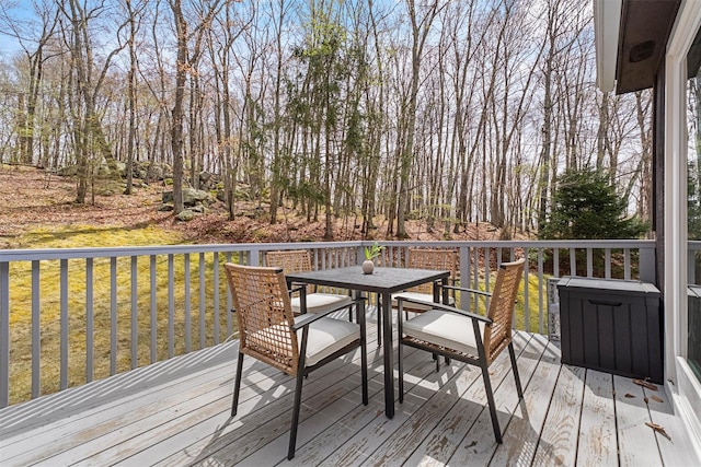wooden terrace with outdoor dining area and a yard