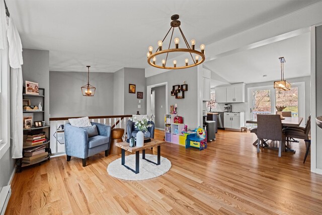 living room featuring an inviting chandelier, light wood-type flooring, lofted ceiling, and a baseboard heating unit