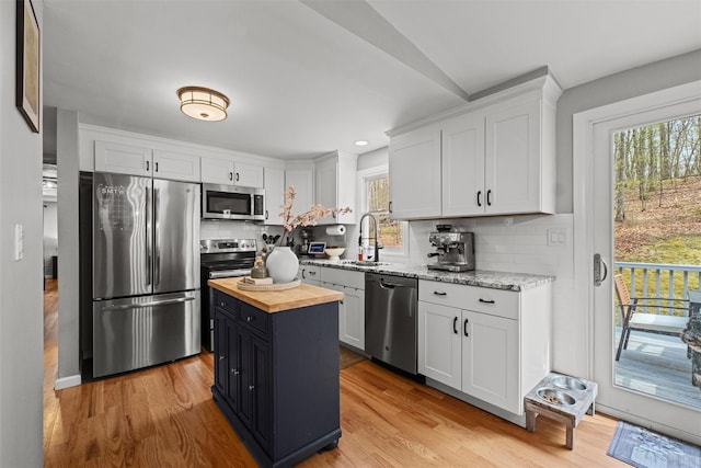 kitchen with butcher block counters, a healthy amount of sunlight, stainless steel appliances, and a sink