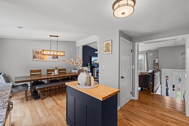 interior space with light wood finished floors, decorative light fixtures, wood counters, and a chandelier