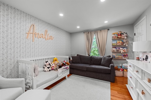 living area with an accent wall, light wood-type flooring, wallpapered walls, and recessed lighting
