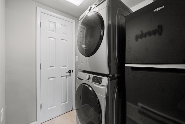clothes washing area featuring baseboards, stacked washer / drying machine, and laundry area