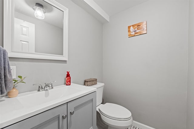 half bathroom featuring toilet, vanity, and baseboards