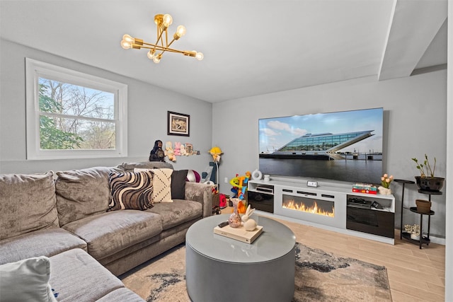 living room with wood finished floors, a notable chandelier, and a glass covered fireplace
