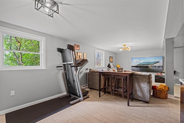 workout room with a chandelier, light wood-type flooring, a baseboard heating unit, and baseboards