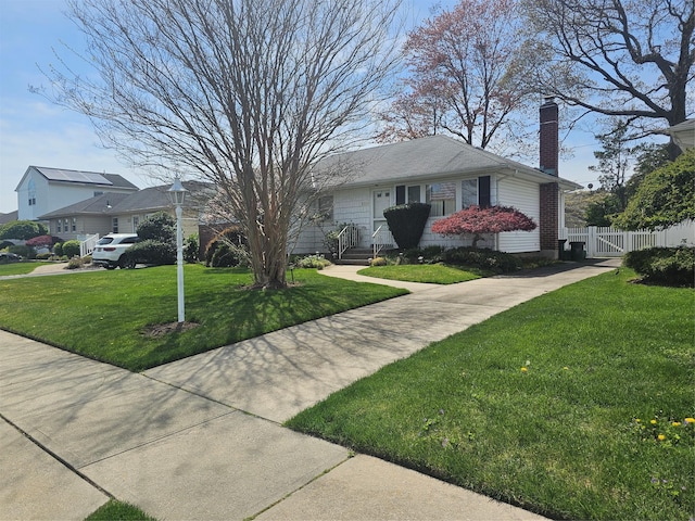 view of front facade featuring a chimney, fence, and a front lawn