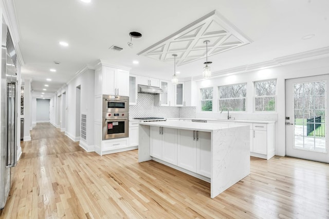 539 Split Rock Rd, Syosset, NY 11791 - kitchen with appliances with stainless steel finishes, white cabinetry, under cabinet range hood, visible vents, and ornamental molding