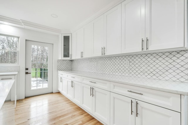 539 Split Rock Rd, Syosset, NY 11791 - kitchen featuring light stone countertops, glass insert cabinets, light wood-type flooring, white cabinets, and tasteful backsplash