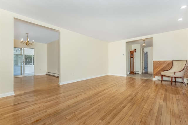 unfurnished living room with baseboard heating, baseboards, a baseboard heating unit, light wood finished floors, and an inviting chandelier