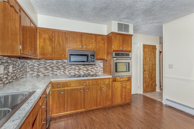 kitchen featuring visible vents, tasteful backsplash, dark wood finished floors, a baseboard radiator, and stainless steel appliances