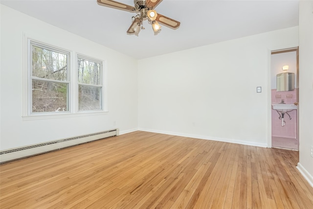 empty room featuring light wood-style floors, baseboards, ceiling fan, and a baseboard heating unit
