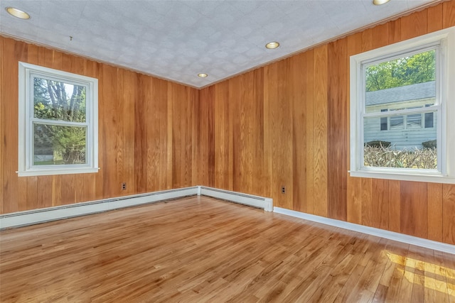 unfurnished room with recessed lighting, plenty of natural light, wood walls, and wood finished floors
