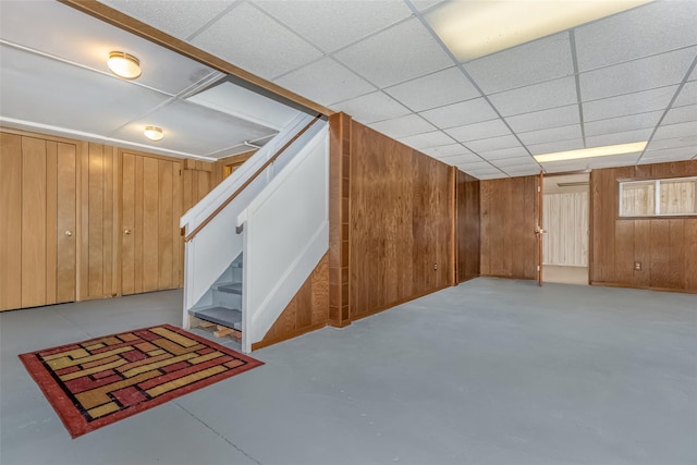 finished below grade area featuring wood walls and stairway