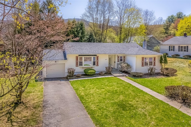ranch-style home featuring an attached garage, a shingled roof, a front yard, and aphalt driveway
