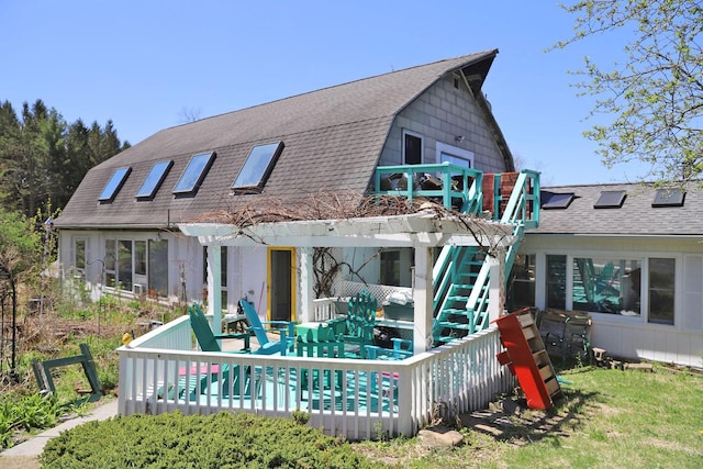 rear view of house featuring a deck, a gambrel roof, roof with shingles, and stairway
