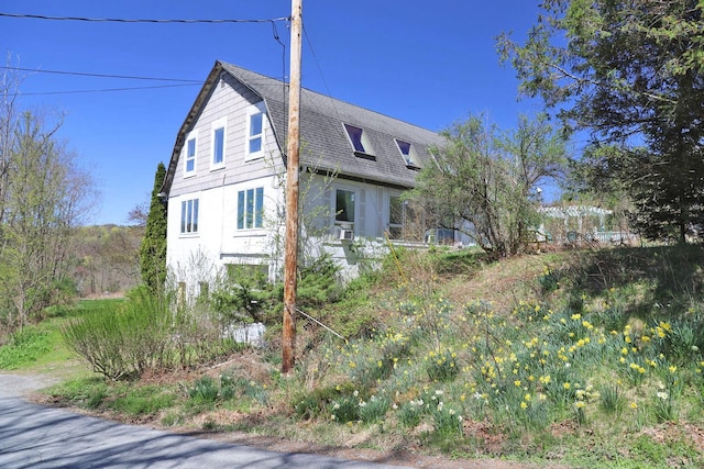view of property exterior with a gambrel roof and roof with shingles