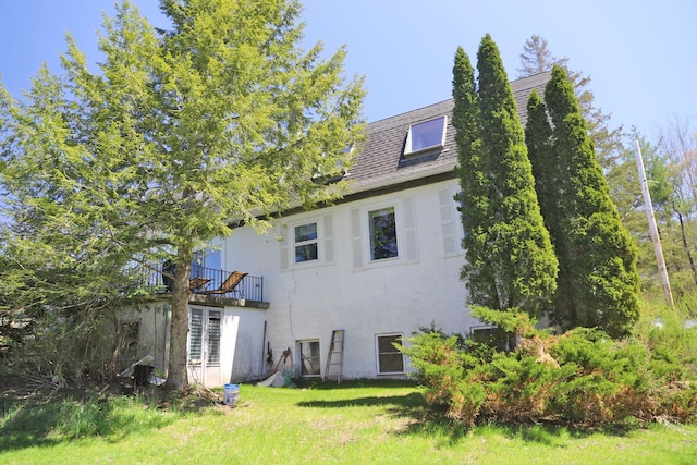 back of property featuring stucco siding, a lawn, and a balcony