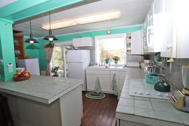 kitchen featuring a sink, tile counters, white cabinets, white appliances, and dark wood-style floors
