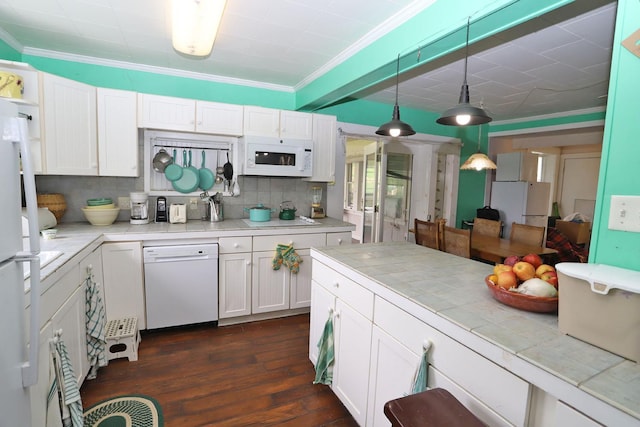 kitchen with white appliances, tasteful backsplash, crown molding, white cabinetry, and tile counters