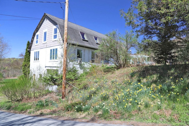 view of side of home featuring a gambrel roof and roof with shingles
