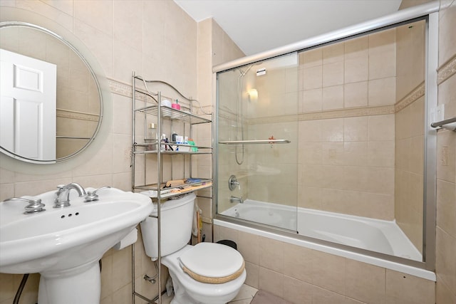 full bathroom featuring toilet, a sink, tile walls, and tiled shower / bath combo