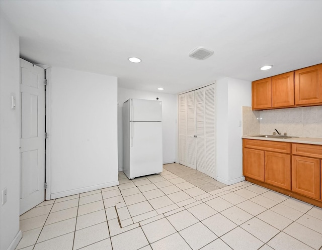 kitchen with recessed lighting, a sink, baseboards, light countertops, and freestanding refrigerator