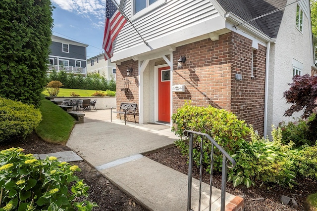 126 Lincoln Ave E, West Harrison, NY 10604 - doorway to property featuring brick siding, roof with shingles, and a patio area