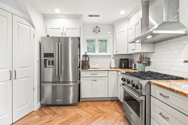 126 Lincoln Ave E, West Harrison, NY 10604 - kitchen with wall chimney range hood, white cabinetry, stainless steel appliances, and decorative backsplash