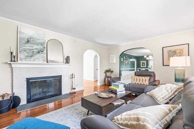 126 Lincoln Ave E, West Harrison, NY 10604 - living room featuring arched walkways, wood finished floors, a chandelier, ornamental molding, and a fireplace