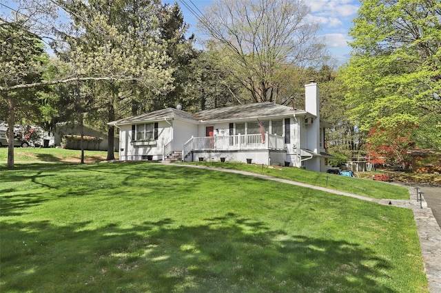 view of front of house featuring a chimney, a porch, and a front lawn