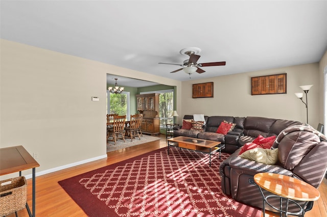 living area with baseboards, ceiling fan with notable chandelier, and wood finished floors