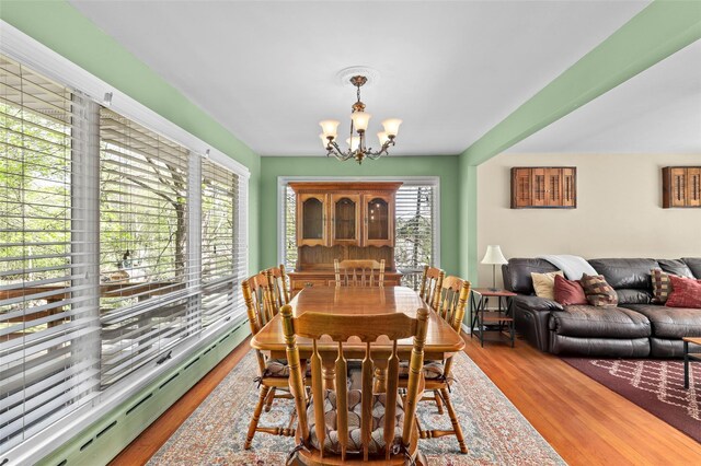 dining area with a notable chandelier, baseboard heating, and wood finished floors